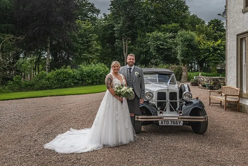Bride and groom beside a vintage wedding car at Stemster House