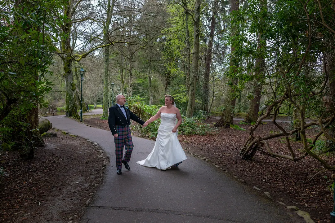Couple walking hand in hand along a woodland path on the Ness Islands, Inverness