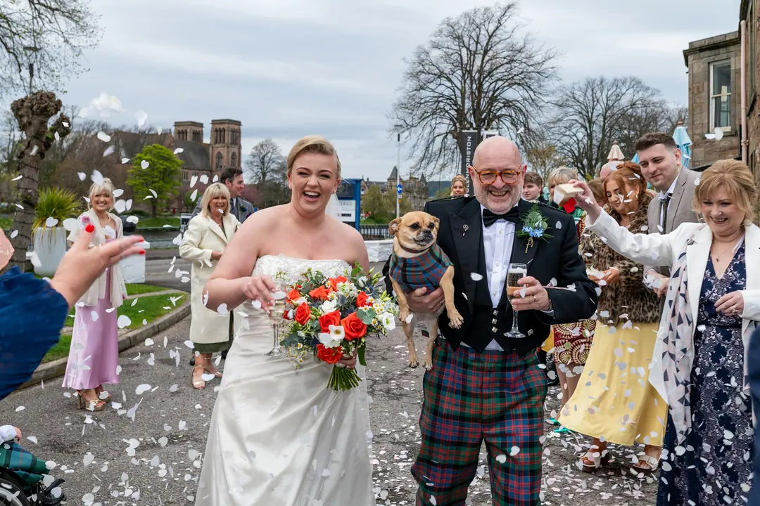 Guests throwing confetti over a bride and her father