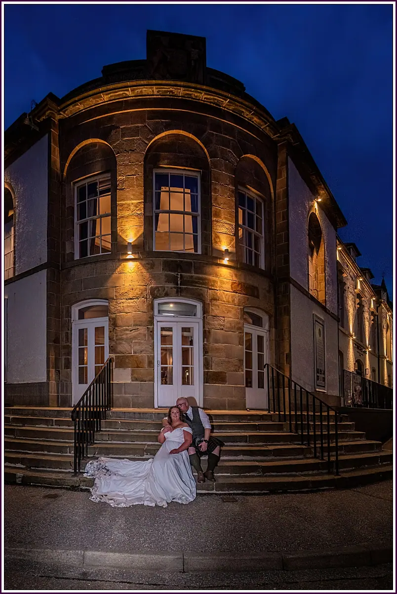 Bride on the steps of the Seafield Arms Hotel at dusk