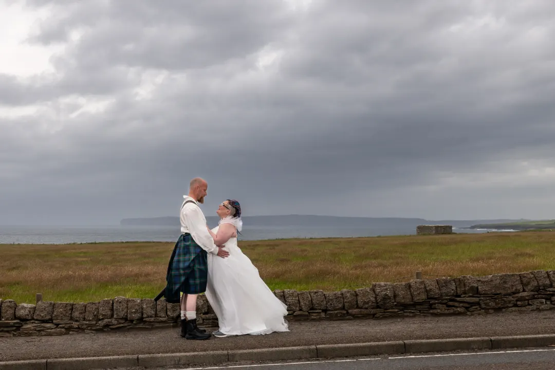 A bride and groom over Scrabster Bay, Caithness with Dunnet Head in the background