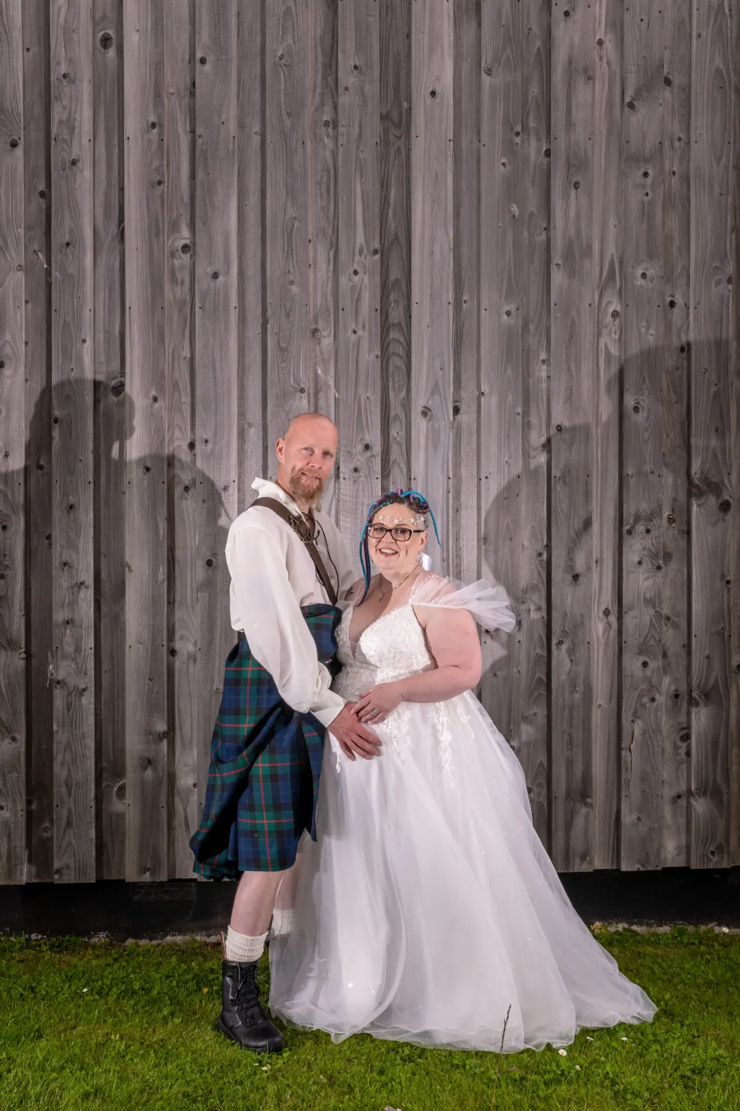 A Bride and Groom against a wooden fence in the grounds of the Weigh Inn Hotel, Thurso, Caithness