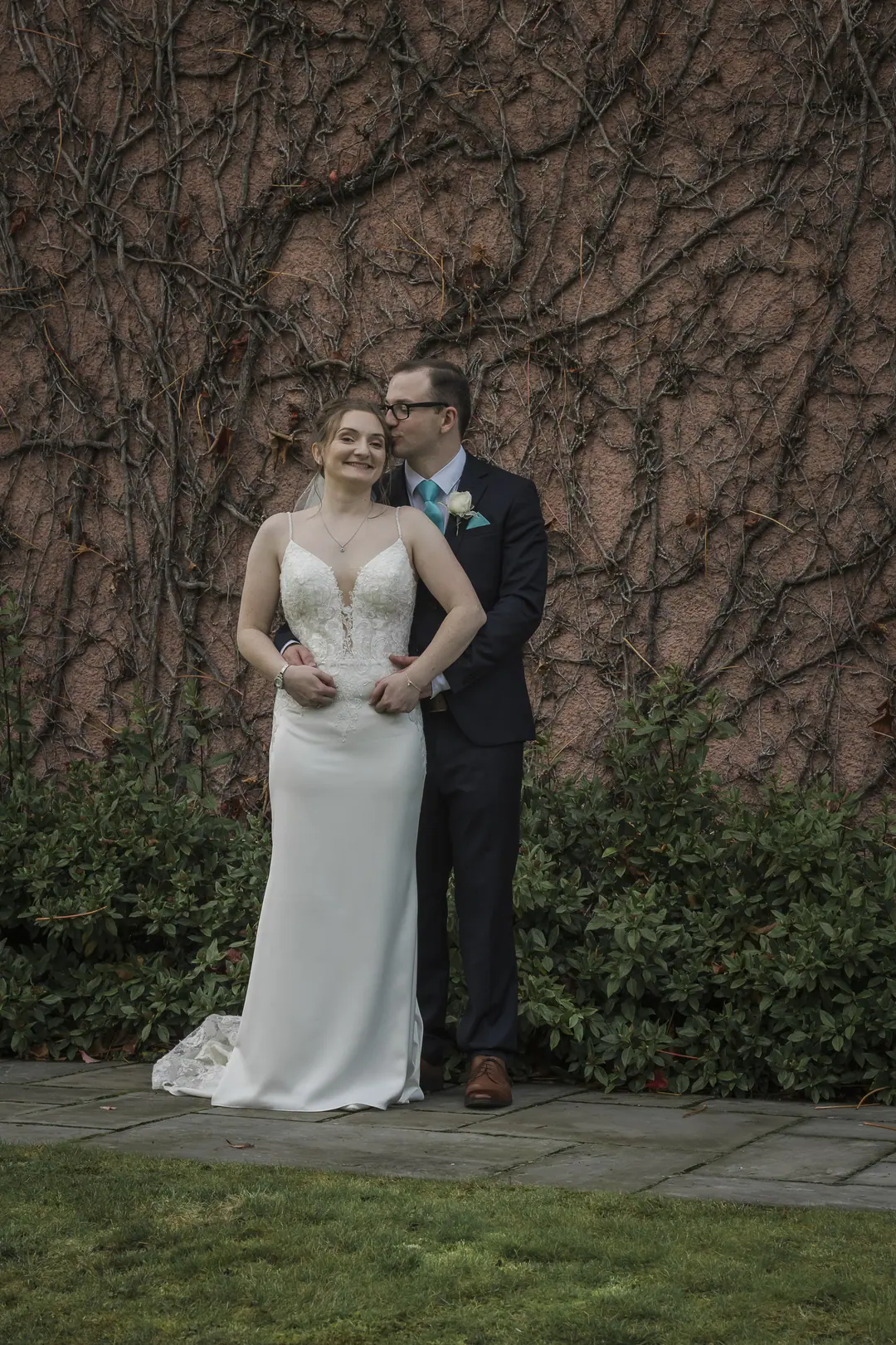 Bride and groom in front of an ivy-covered wall
