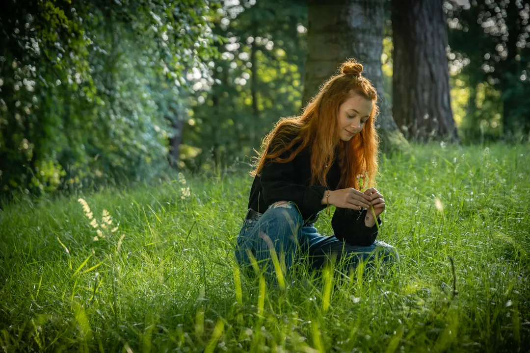 Young woman sitting in long summer grass