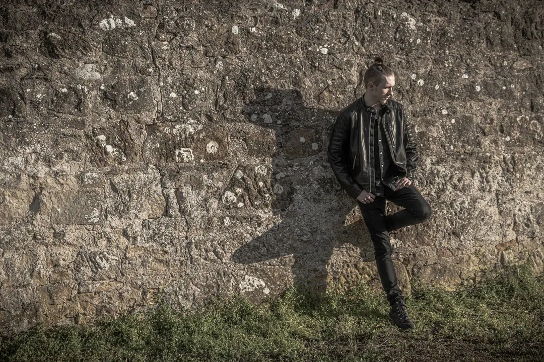 Man leaning against an old stone wall