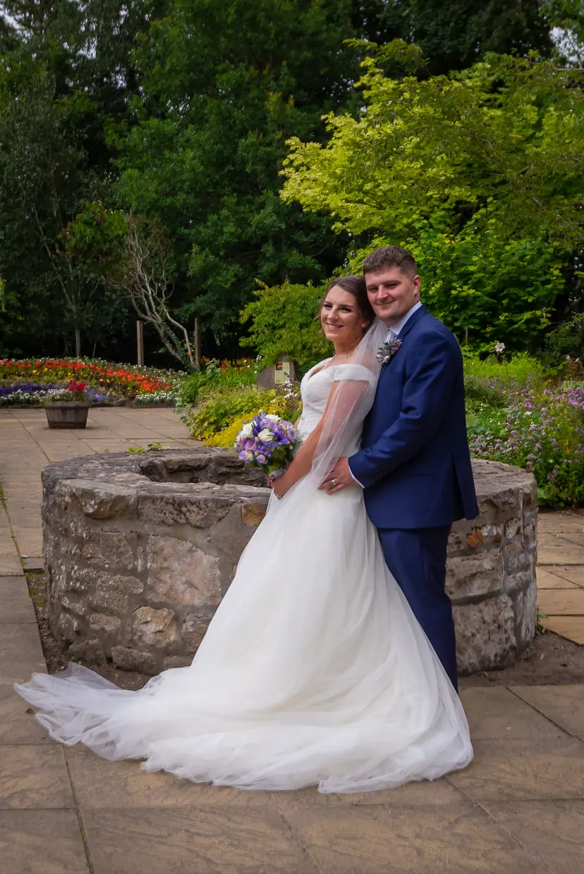 Couple beside an old stone well in a flower garden