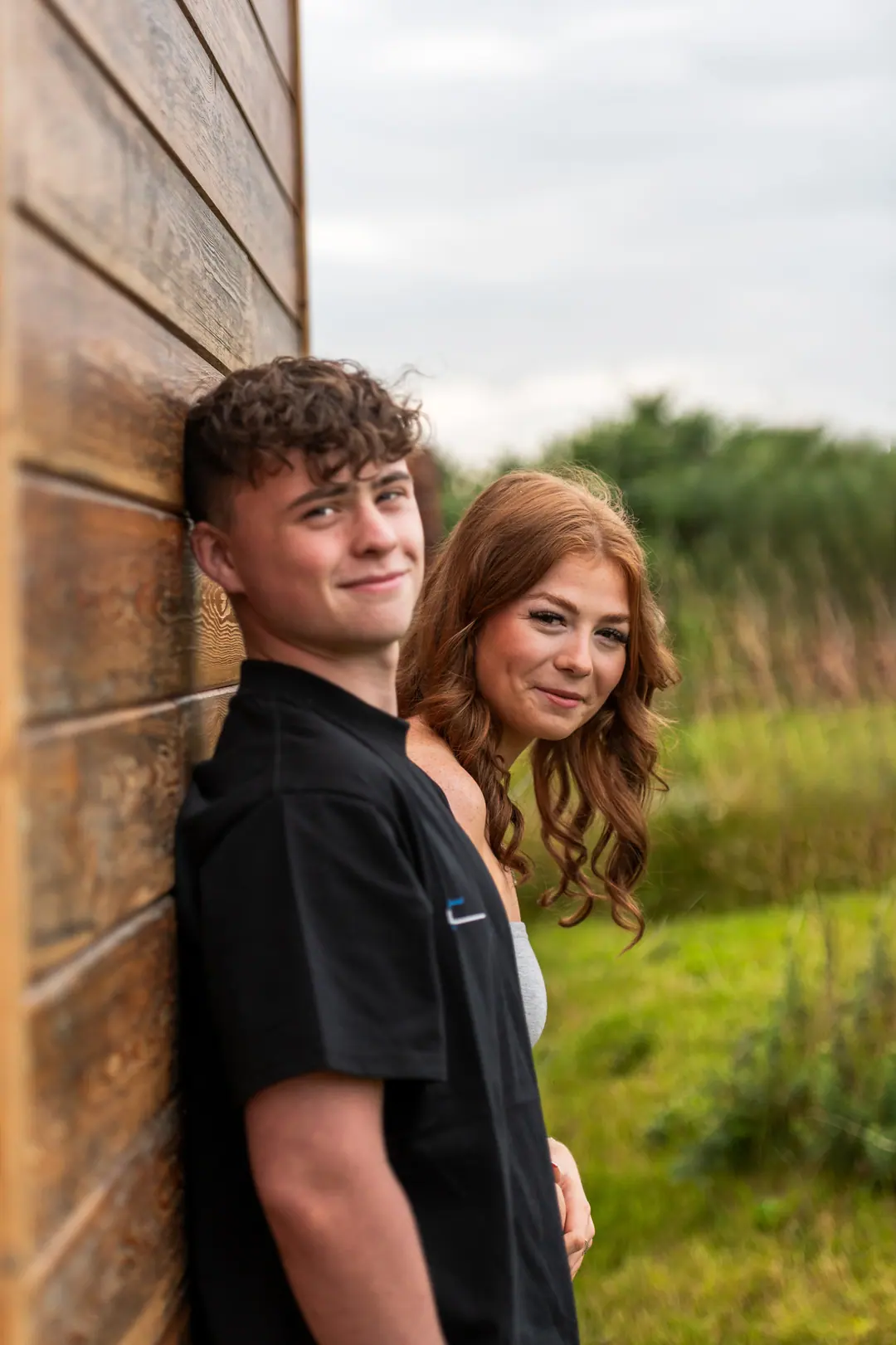 Couple leaning against a timber wall