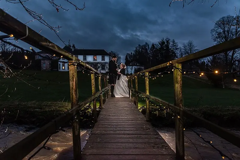 Couple on a lit wooden walkway at dusk