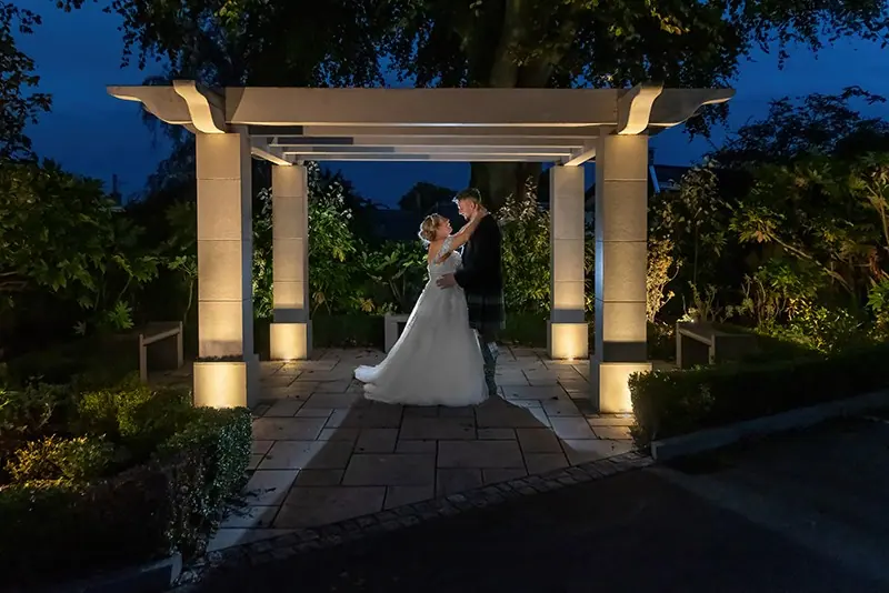 Couple beneath an illuminated pergola at night