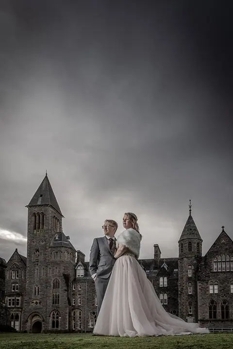 Couple in front of a gothic castle under a stormy sky