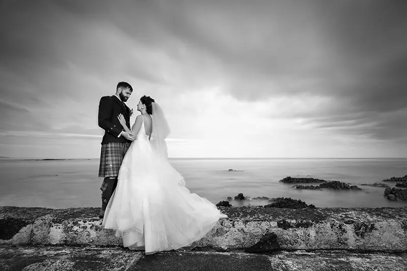 Black-and-white portrait of a couple on a rocky shore