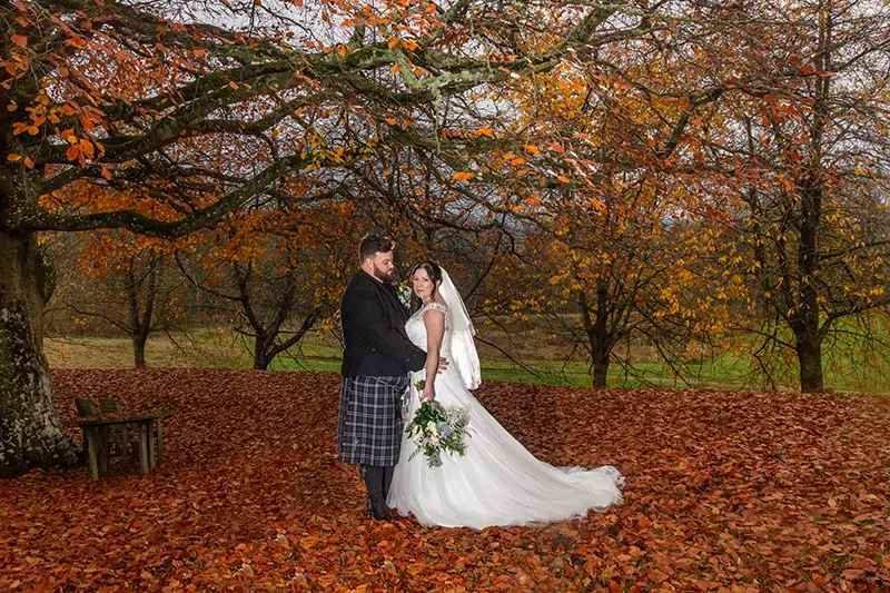 Couple among autumn leaves beneath copper trees