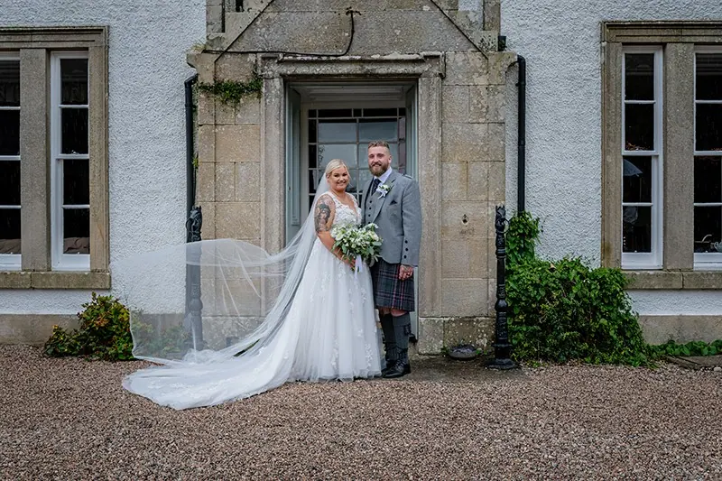 Couple at the doorway of a stone mansion