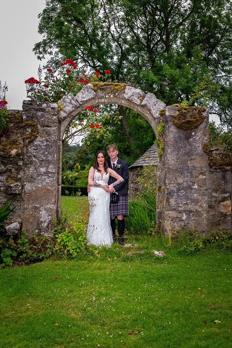 Couple beneath a stone archway in a walled garden