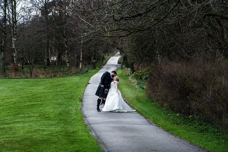 Groom dipping the bride on a woodland path