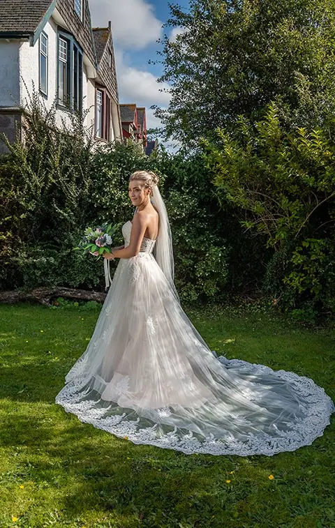 Bride with a long cathedral veil on a garden lawn