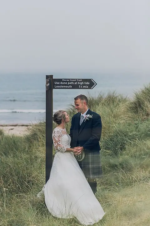 Couple in the dunes beside a beach signpost