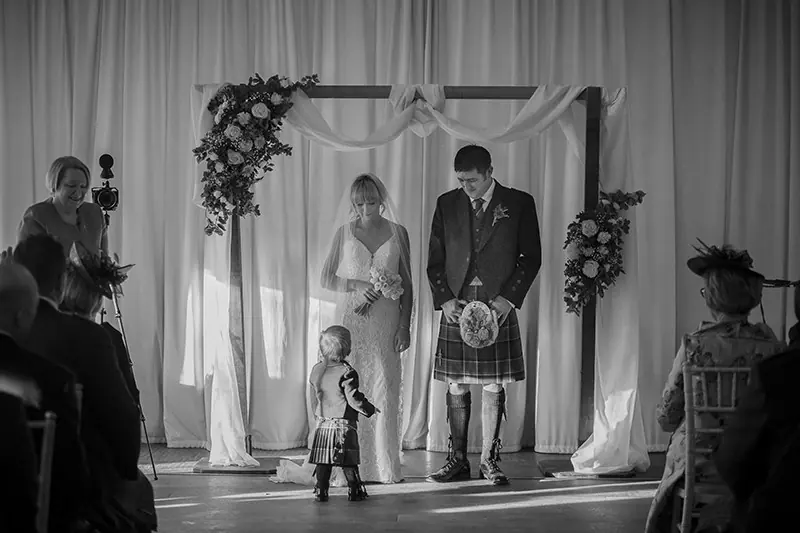 Black-and-white ceremony beneath a floral arch